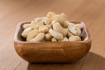 Wooden bowls of cashews on wooden table.