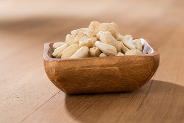 Wooden bowls of cashews on wooden table.