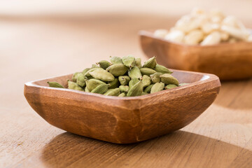 Bowl of cardamom and cashew on table.