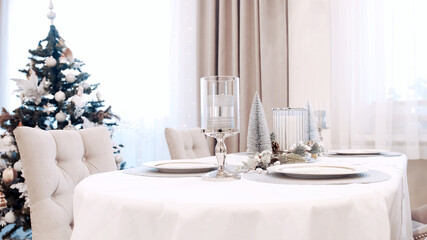 A girl in a white dress serves plates at the Christmas table. Festive table setting