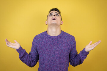 Young caucasian man over isolated yellow background clueless and confused expression with arms and...
