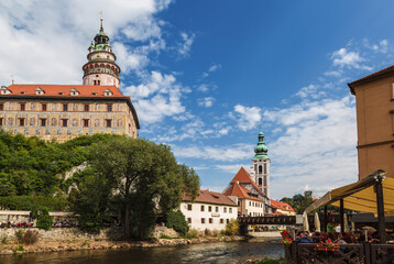 Obraz premium View of Cesky Krumlov, Krumlov Castle, St. Jost Church, Vltava River and people sitting in cafes and restaurants. Czech Republic