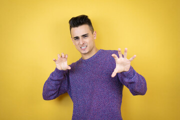 Young caucasian man over isolated yellow background smiling funny doing claw gesture as cat,...
