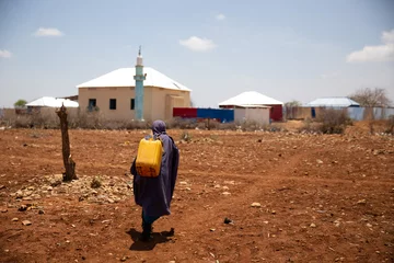 Schilderijen op glas Kids walking home after water distribution during deadly drought in Somalia © Mustafa Olgun