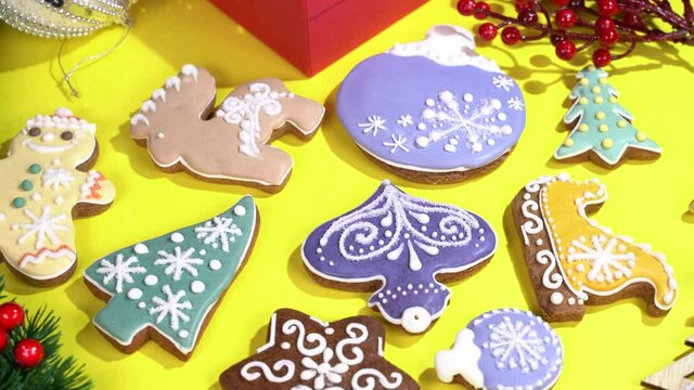 Christmas gingerbread with shape of new year trre, bull, snowflake, bell, deer, angel and festive deocrations rotates on yellow background.