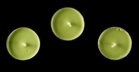 Green tea light candle in aluminum holder isolated on black background, top view
