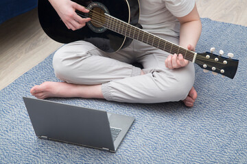 Online guitar training.Young man learn to play guitar through online training.