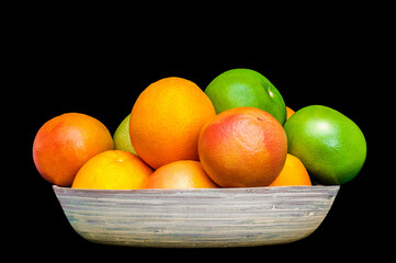 Isolated plate full of citruses fruits. Set of oranges, tangerines, limes, pummelo, grapefruits on black background.