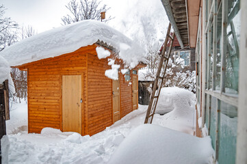 Real Russian winter, when frost and a lot of snow, in the country village, with small houses, dumping snow from the roof of a house