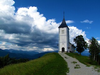 Fototapeta na wymiar Church of Saints Primus and Felician at Jamnik in Gorenjska, Slovenia with dark storm clouds above
