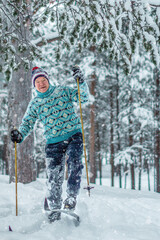 beautiful happy healthy elderly man in a blue knitted sweater and cap in a winter park spruce...