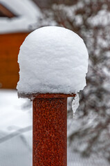 Rusty, iron pillar with a thick cap of snow at the top, snowy, frosty winter