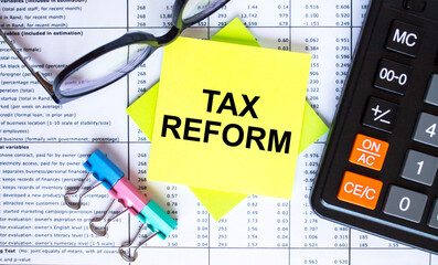 Text Tax Reform on yellow stickers with calculator, eyeglasses and paper clips