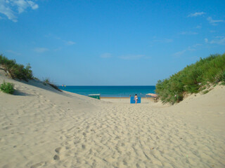 the road to the sandy beach on the background of the sea and blue sky in summer