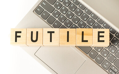 Word futile. Wooden cubes with letters isolated on a laptop keyboard. Business Concept image.