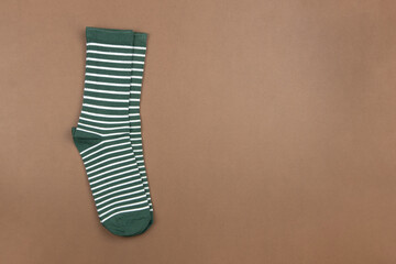 Pair of green striped socks on brown background, flatly, minimal style, top view, copy space. Concept male clothing, housekeeping, sorting, decluttering, organizing. Horizontal format