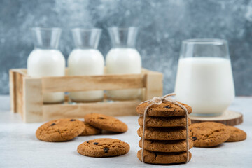Glass and jar of milk with stack of cookies on marble table