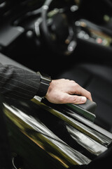 Fototapeta premium Businessman driving a sports luxury car.Hand on the handle. Close-up of man in formal attire opening car door