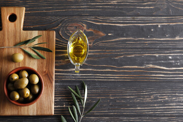 Composition of green olives, olive oil, on a wooden background with space for text.