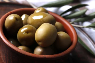 Foto op Plexiglas Composition of green olives, olive oil, marinade on a wooden background close up © PANDA