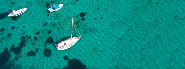 Fototapeta premium Aerial drone ultra wide photo of traditional fishing boat and yacht anchored in paradise bay of Ornos, Mykonos island, Cyclades, Greece