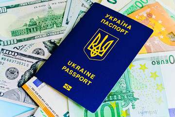The Ukrainian biometric passport is on paper euro bills and dollars. Concept: increase of salaries, Ukrainians go abroad to work in Europe, Immigration to work, vacation abroad, visa for Europe..