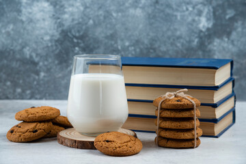 Glass of milk, sweet cookies and book on marble table