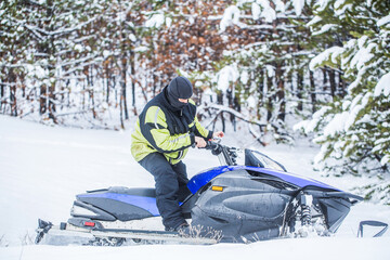 Man is riding snowmobile in mountains. Pilot on a sports snowmobile in a mountain forest. Athlete rides a snowmobile in the mountains. Snowmobile in snow. Concept winter sports