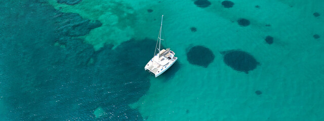 Aerial drone ultra wide photo of Catamaran sail boat anchored in tropical exotic bay with emerald sea
