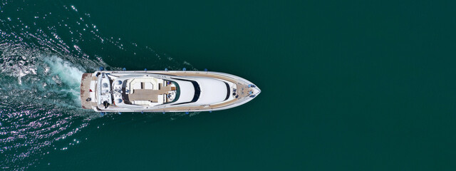 Aerial drone ultra wide photo of luxurious yacht with wooden deck anchored in deep blue Mediterranean Sea