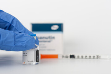 Obraz premium Human fingers in gloves, syringe with needle, vial and paper box with Covid-19 vaccines.