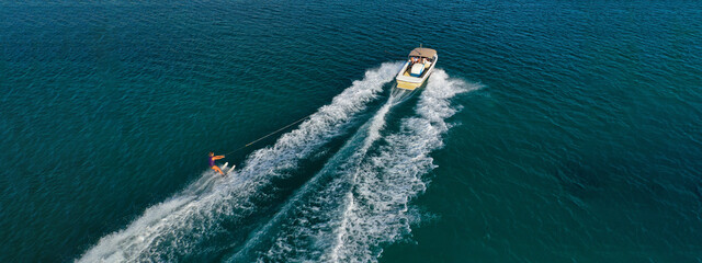 Aerial drone ultra wide photo of extreme powerboat water ski cruising in high speed in tropical turquoise bay