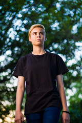 Young woman beauty Tomboy lifestyle with blonde short hair posing in casual clothes in a park in...