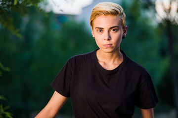 Young woman beauty Tomboy lifestyle with blonde short hair posing in casual clothes in a park in...