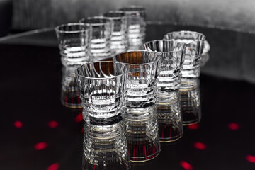 Clean transparent faceted drink glasses stand on a black