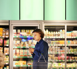 Teenager shopping in supermarket, reading product information