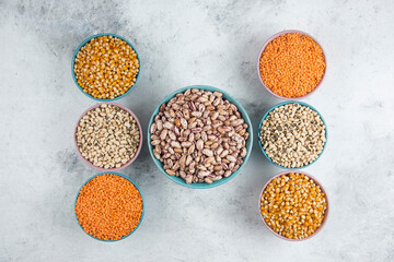 Bunch of various uncooked beans, corns and red lentils on marble surface