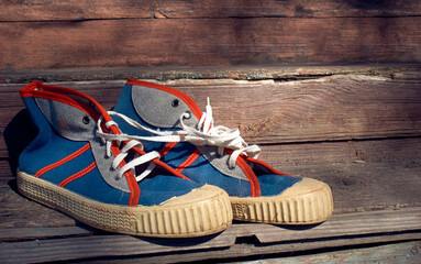 A pair of retro blue gumshoes or sneakers stand on old wooden steps