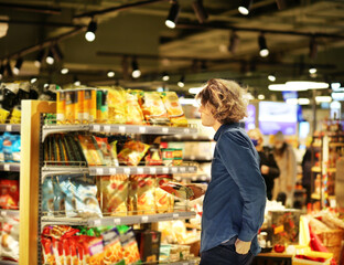 Teenager shopping in supermarket, reading product information