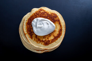 a stack of browned pancakes with sour cream