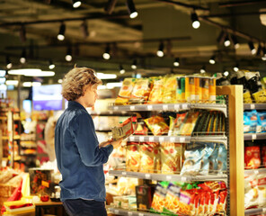 Teenager shopping in supermarket, reading product information