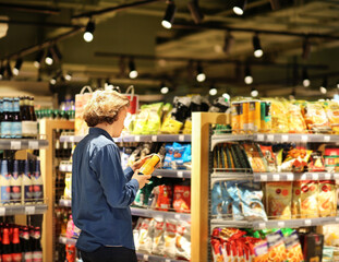 Teenager shopping in supermarket, reading product information