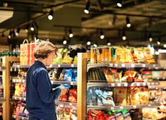 Teenager shopping in supermarket, reading product information