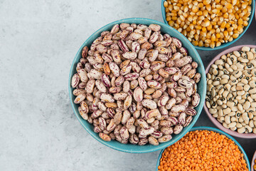Bunch of various uncooked beans, corns and red lentils on marble surface