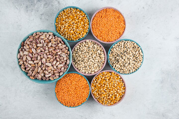 Bunch of various uncooked beans, corns and red lentils in bowls