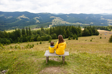 Mother and son tourists in Carpathians. Hiking. Mom and boy looking on Panorama of mountains...