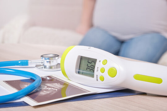 ultrasound picture, stethoscope and non-contact thermometer, pregnant woman on the background
