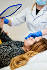 Girl patient looks in the mirror during a facial skin care procedure.