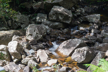 Naklejka na ściany i meble Water stream flowing between rocks in the river.