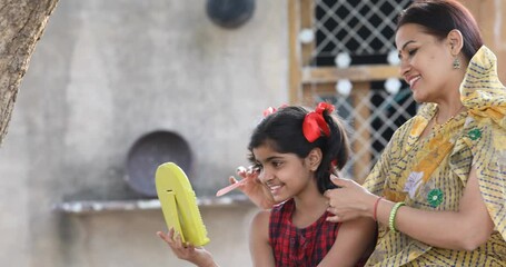 Joyful girl with mother having fun looking into handheld mirror